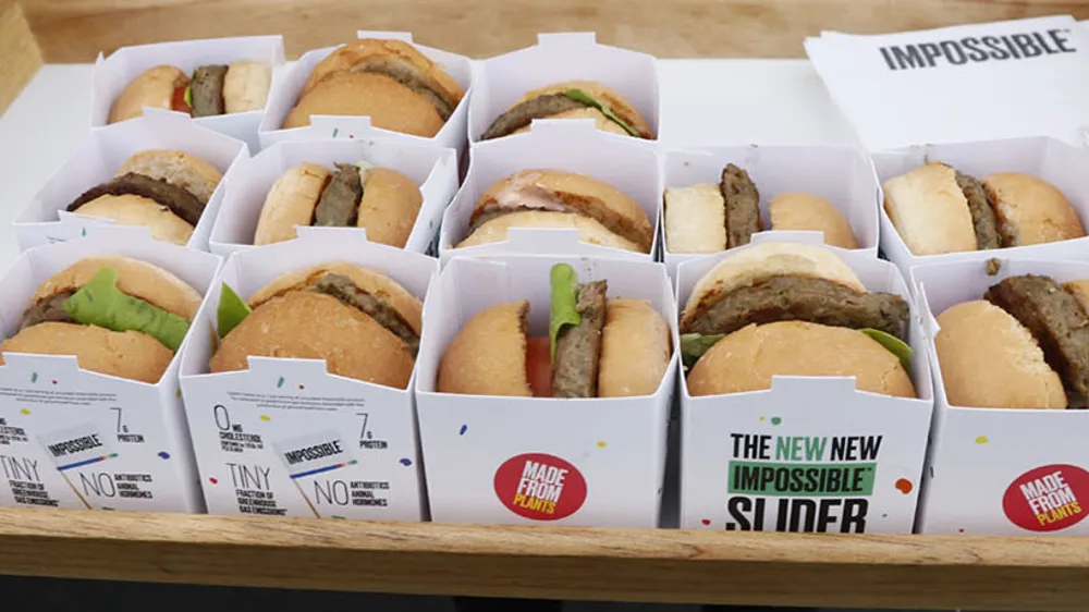ALT Text: a person holding a tray of 16 impossible burgers (fake meat) individually wrapped 