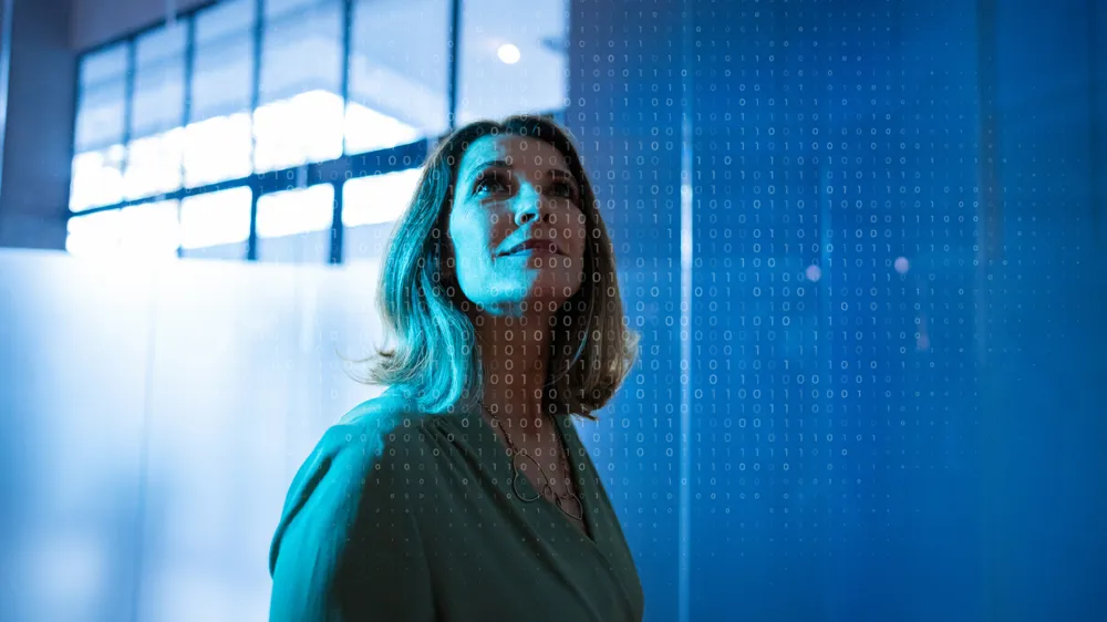 ALT Text: A woman looking up with a bunch of zeros and ones filtered in front